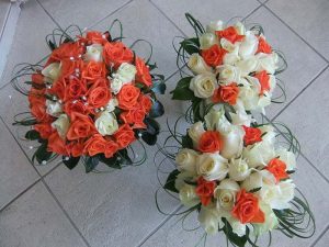 Wedding posies with white and orange roses with diamonds and camellia leaves